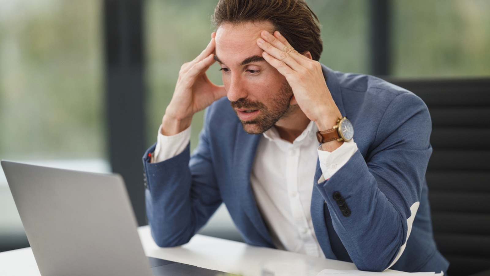 Stressed business owner looking at a laptop while dealing with email and account access problems